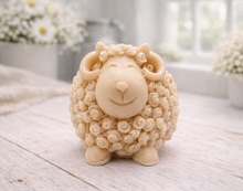Load image into Gallery viewer, A highly detailed handmade vegan soap sculpted in the shape of a sturdy ram with a thick coat of tight, curly wool and large, elegant curved horns, displayed on a light wooden surface in a bright farmhouse setting.
