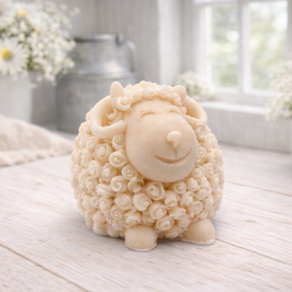 A highly detailed handmade vegan soap sculpted in the shape of a sturdy ram with a thick coat of tight, curly wool and large, elegant curved horns, displayed on a light wooden surface in a bright farmhouse setting.