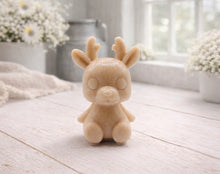 Load image into Gallery viewer, A 3D handmade vegan soap crafted into a cute, sitting baby reindeer with small antlers, rounded features, and a sweet expression, set against a bright farmhouse window.

