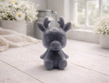 Load image into Gallery viewer, A 3D handmade vegan soap crafted into a cute, sitting baby reindeer with small antlers, rounded features, and a sweet expression, set against a bright farmhouse window.
