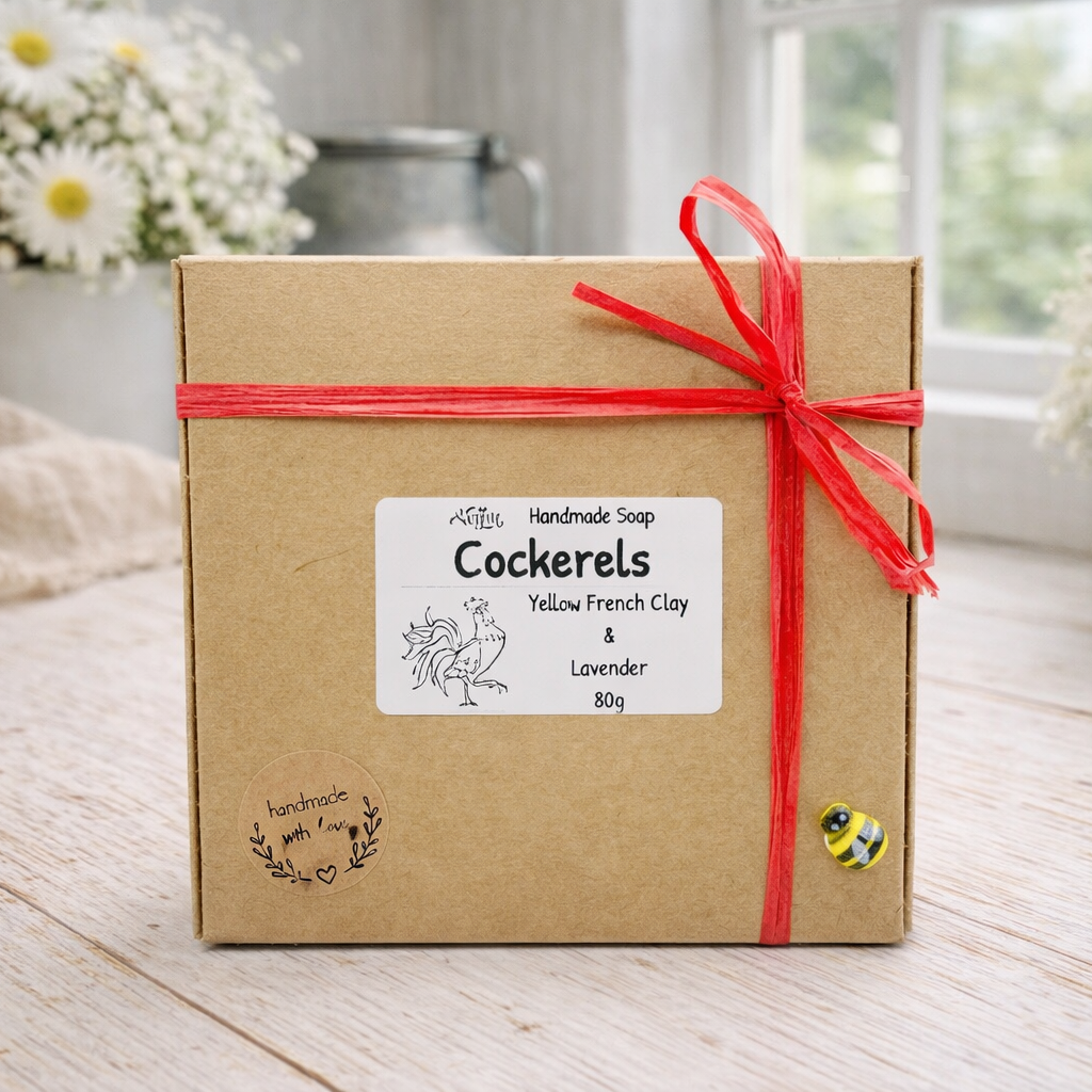 Box of handmade soap with a red ribbon on a wooden surface with flowers in the background