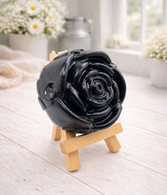 Load image into Gallery viewer, A handmade vegan soap, intricately sculpted in the shape of a large, blooming rose flower with layered petals, displayed on a small wooden easel against a bright win
