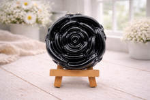 Load image into Gallery viewer, A handmade vegan soap, intricately sculpted in the shape of a large, blooming rose flower with layered petals, displayed on a small wooden easel against a bright win
