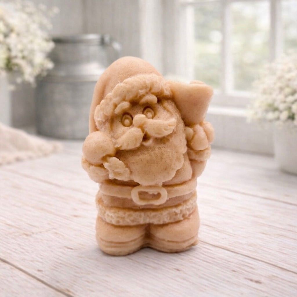 A highly detailed 3D handmade vegan soap featuring a Father Christmas carrying a large sack of gifts over his shoulder and holding a bell, featuring an intricate curly beard and fur-trimmed suit, set against a festive holiday background.