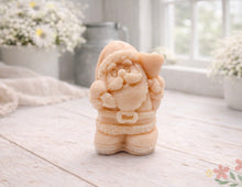 Load image into Gallery viewer, A highly detailed 3D handmade vegan soap featuring a Father Christmas carrying a large sack of gifts over his shoulder and holding a bell, featuring an intricate curly beard and fur-trimmed suit, set against a festive holiday background.
