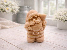 Load image into Gallery viewer, A highly detailed 3D handmade vegan soap featuring a Father Christmas carrying a large sack of gifts over his shoulder and holding a bell, featuring an intricate curly beard and fur-trimmed suit, set against a festive holiday background.
