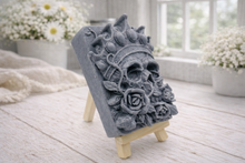 Load image into Gallery viewer, handmade vegan soap gift featuring a detailed relief of a skull wearing a crown, surrounded by a border of roses, displayed on a small wooden easel.
