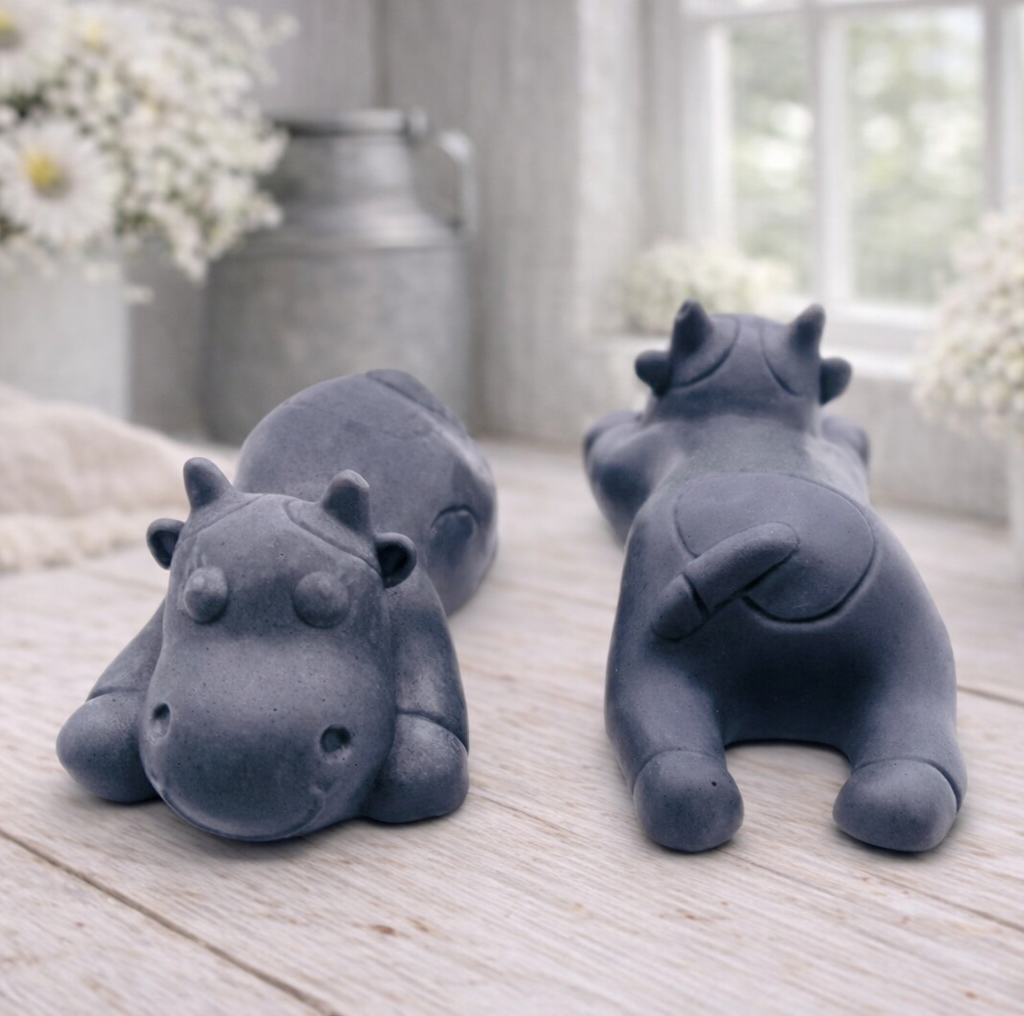 A handmade vegan soap gift set featuring two soaps sculpted into cute, sleeping cows, presented in a brown kraft box tied with a red raffia ribbon and a small ladybird embellishment.
