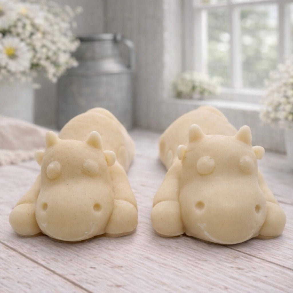A handmade vegan soap gift set featuring two soaps sculpted into cute, sleeping cows, presented in a brown kraft box tied with a red raffia ribbon and a small ladybird embellishment.