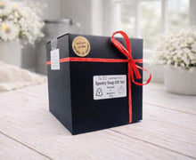 Load image into Gallery viewer, Black gift box with red ribbon and 'Spooky Soap Gift Set' label on a light wooden surface.

