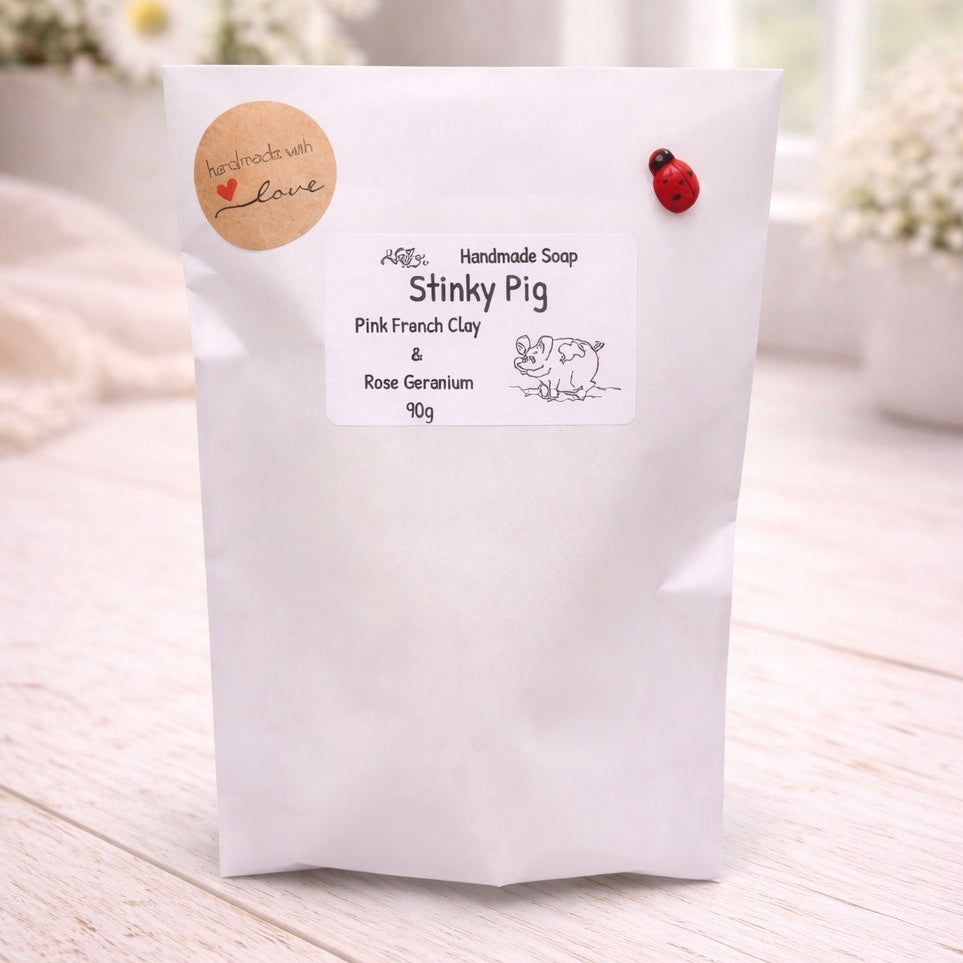 Handmade soap packaging with 'Stinky Pig' branding on a light wooden surface.
