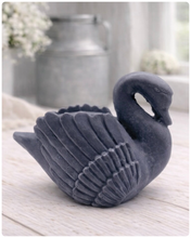 Load image into Gallery viewer, handmade vegan soap, sculpted into the shape of a graceful swan with detailed feathering on its wings and a curved neck, displayed on a light wooden surface in a bright farmhouse setting.
