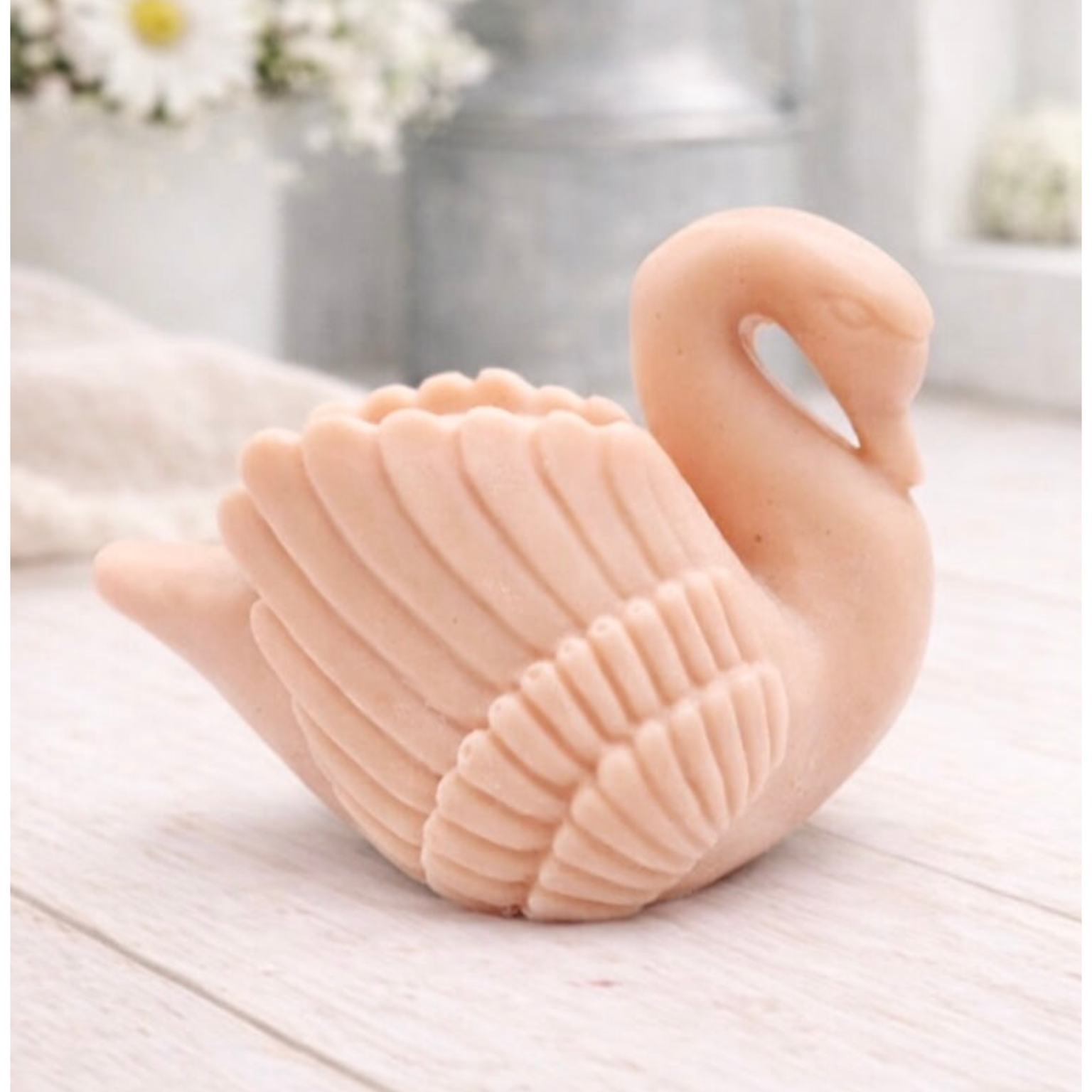 handmade vegan soap, sculpted into the shape of a graceful swan with detailed feathering on its wings and a curved neck, displayed on a light wooden surface in a bright farmhouse setting.