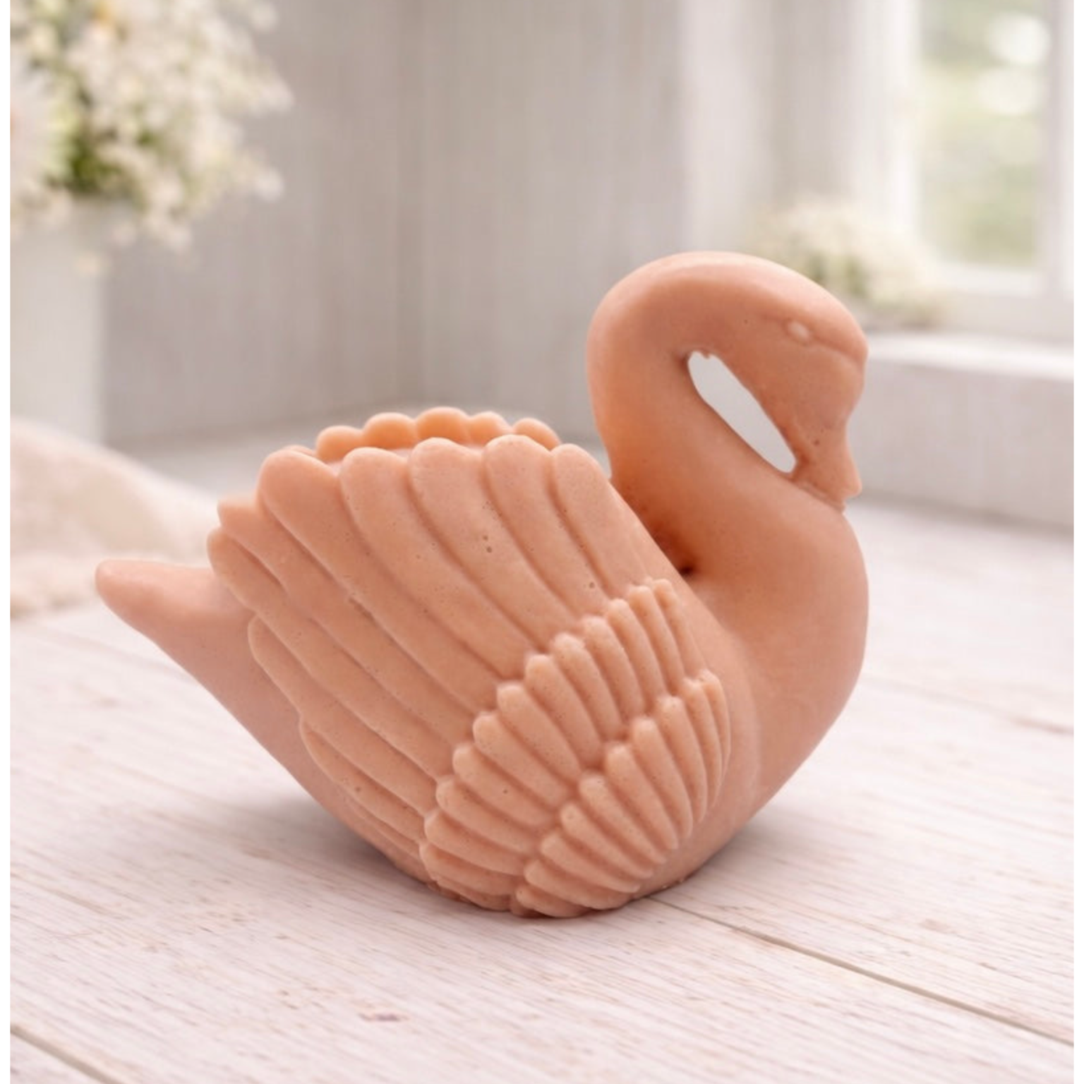 handmade vegan soap, sculpted into the shape of a graceful swan with detailed feathering on its wings and a curved neck, displayed on a light wooden surface in a bright farmhouse setting.