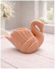 Load image into Gallery viewer, handmade vegan soap, sculpted into the shape of a graceful swan with detailed feathering on its wings and a curved neck, displayed on a light wooden surface in a bright farmhouse setting.
