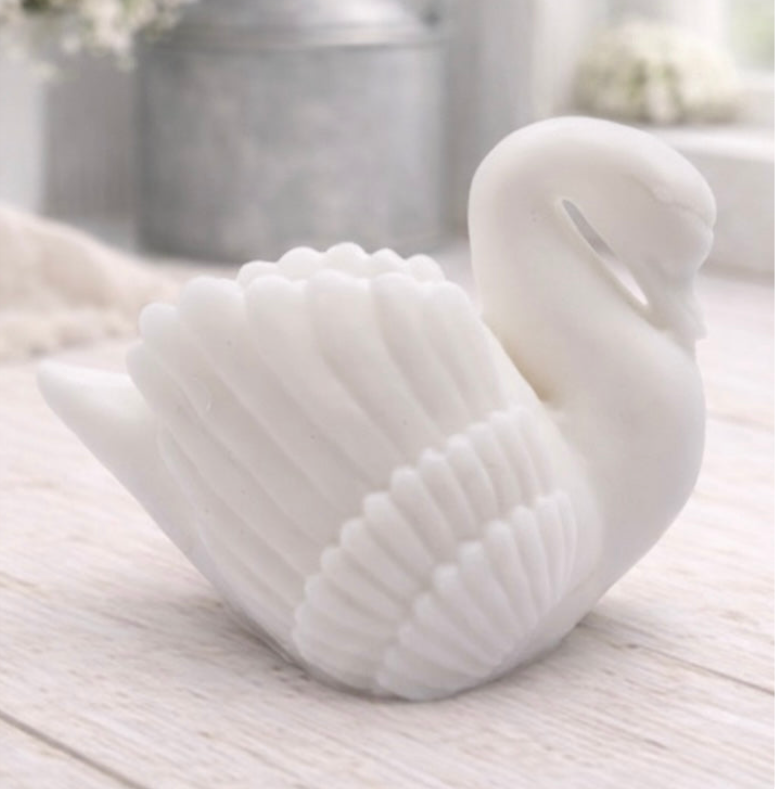 handmade vegan soap, sculpted into the shape of a graceful swan with detailed feathering on its wings and a curved neck, displayed on a light wooden surface in a bright farmhouse setting.