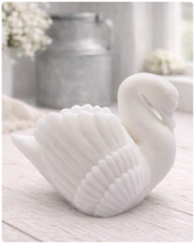 Load image into Gallery viewer, handmade vegan soap, sculpted into the shape of a graceful swan with detailed feathering on its wings and a curved neck, displayed on a light wooden surface in a bright farmhouse setting.
