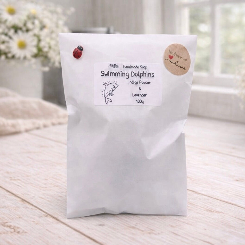 White bag labeled 'Swimming Dolphins' on a wooden surface with flowers in the background