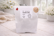 Load image into Gallery viewer, Handmade soap package labeled 'Voodoo Doll' on a wooden surface with flowers in the background.
