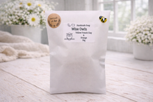Load image into Gallery viewer, White bag with a label on a wooden surface with flowers in the background
