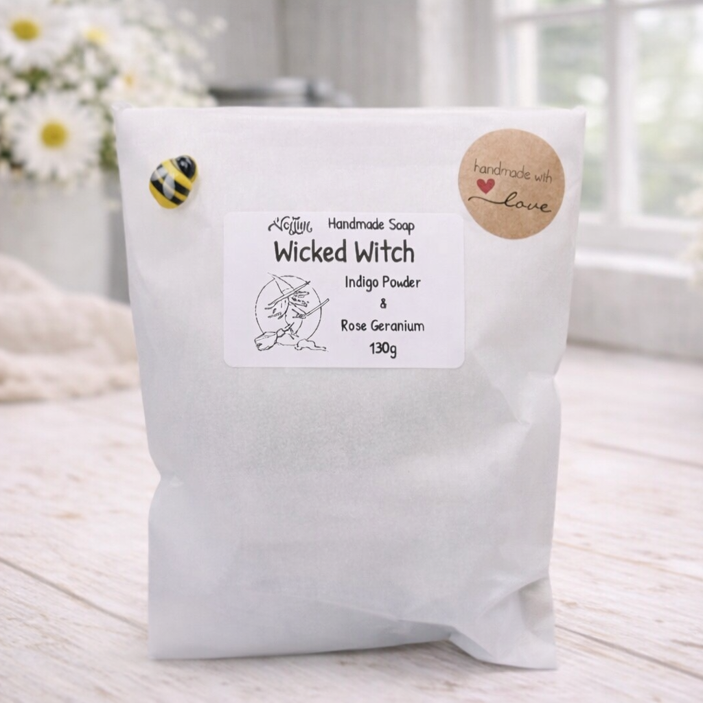 White soap package with a label on a light wooden surface, surrounded by flowers.