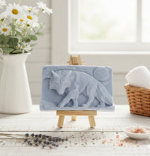Load image into Gallery viewer, handmade vegan soap by Soap Simple Creations featuring  a wolf walking under a full moon, displayed on a wooden easel in farmhouse decor bathroom.

