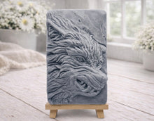 Load image into Gallery viewer, A rectangular handmade vegan soap featuring a highly detailed, 3D relief carving of a wolf's head in profile with a thick, textured mane, displayed on a miniature wooden easel.

