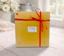 Load image into Gallery viewer, Brown gift box with a red ribbon on a wooden surface
