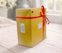 Load image into Gallery viewer, Brown gift box with a red ribbon on a light wooden surface
